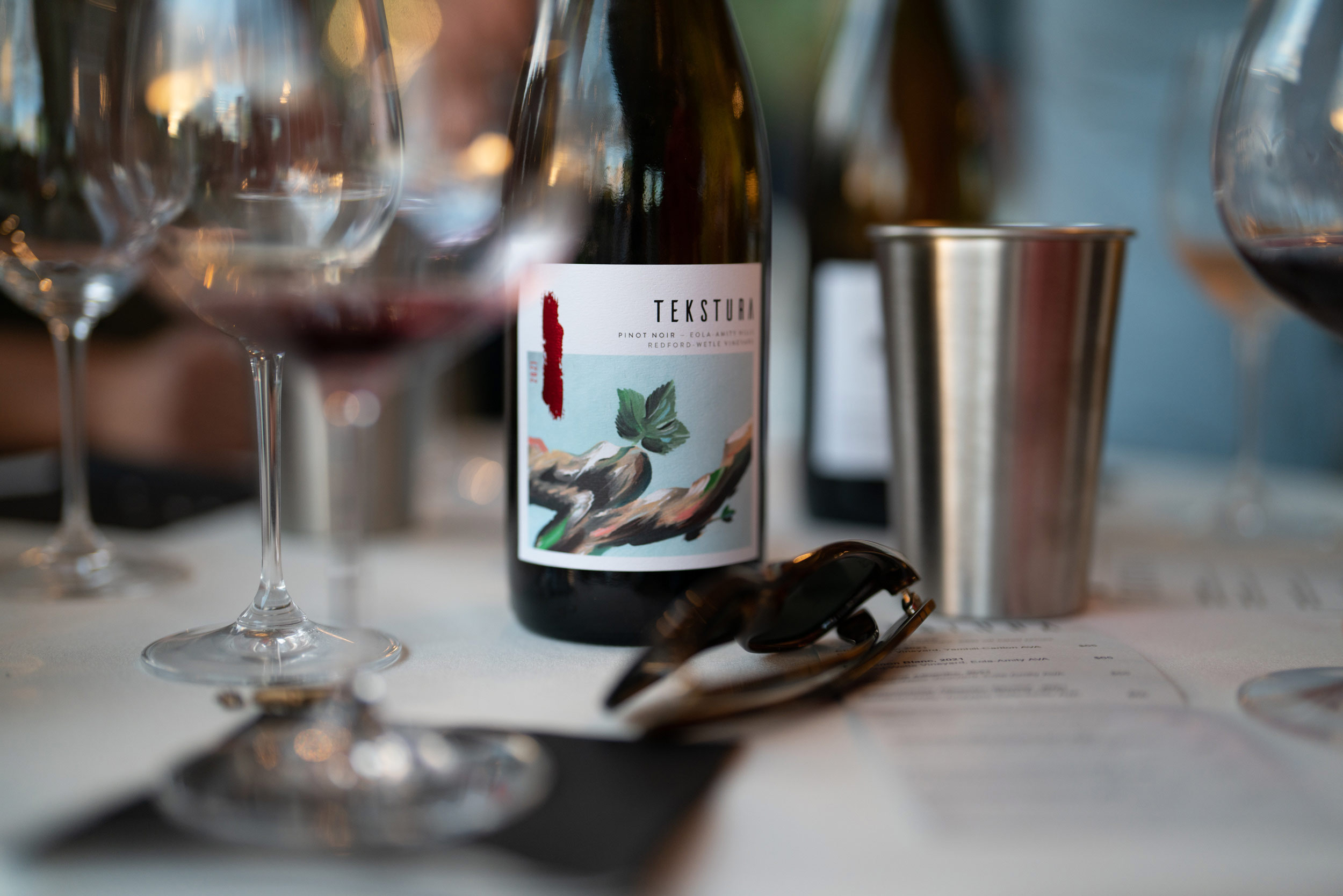 Bottle of Tekstura Pinot Noir on a table with glasses
